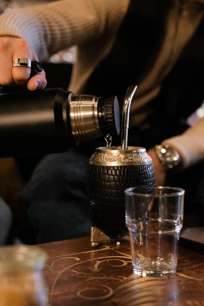 Pouring hot water from a thermos into a yerba mate gourd